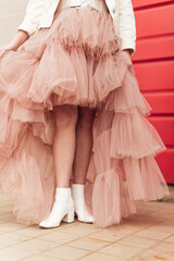 Stylish girl in pink tulle dress and white boots
