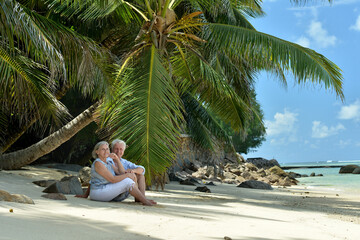 Portrait of elderly couple resting on beach. Travel