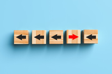 Fototapeta premium Wooden blocks with arrows with one stand out from the crowd and move forward on blue background. Concept of innovation, solutions, uniqueness, individuality and thinking differently. 3d rendering.