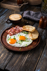 Fried eggs with bacon and herbs, 2 white bread toasts. On the table is a napkin, spices, a glass of champagne. Dark brown wooden background. Breakfast menu for cafe, restaurant, bar.