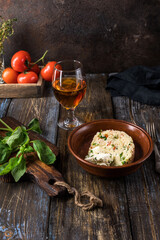 Plate of couscous with tomatoes, vegetables and feta cheese. Basil leaves, tomatoes, herbs and teapot with cup are on a wooden table. Menu for restaurant, cafe, bar. Close up.