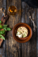 Plate of couscous with tomatoes, vegetables and feta cheese. Basil leaves, tomatoes, herbs and teapot with cup are on a wooden table. Menu for restaurant, cafe, bar. Top view.