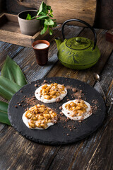 On the serving board is a gourmet dessert green hemisphere with chocolate chips. On a wooden table there is a mug of cappuccino, a sprig of mint in a glass. Close up. Menu for restaurant, cafe, bar.