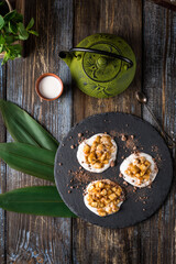 On the serving board is a gourmet dessert green hemisphere with chocolate chips. On a wooden table there is a mug of cappuccino, a sprig of mint in a glass. Top view. Menu for restaurant, cafe, bar.