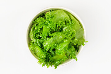 A bowl of frillis lettuce leaves on  a white background. Top view. - obrazy, fototapety, plakaty