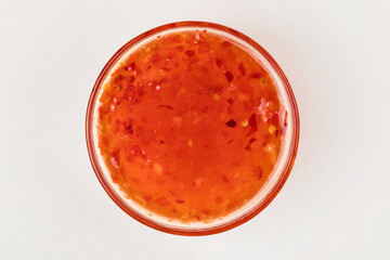 A cup with sweet chili sauce. White background. Top view.