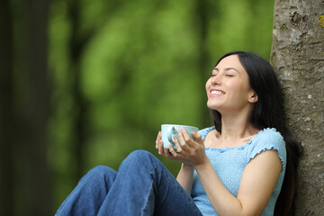 Asian woman enjoying coffee relaxing in a park