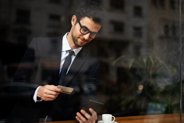 Handsome businessman enjoy in fresh coffee. Young man with credit card and phone