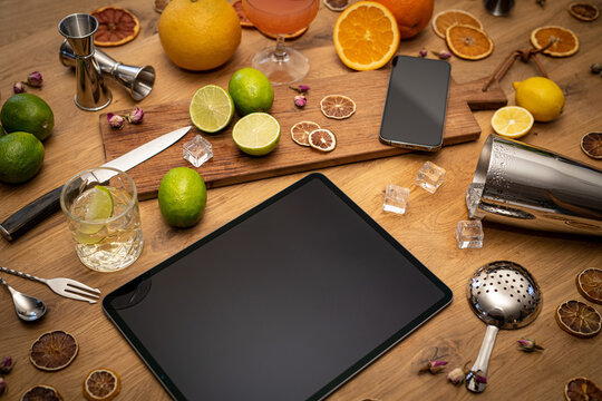 Online Cocktail Course With Blank Tablet, Smartphone And Bartender Tools On Wood Kitchen Table