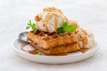 ice cream with waffles, caramel syrup and fresh mint on a white dish