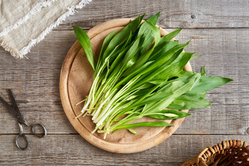 Fresh wild garlic leaves on a wooden table, top view