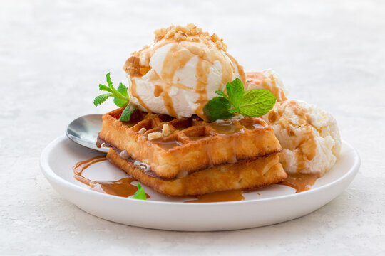 ice cream with waffles, caramel syrup and fresh mint on a white dish