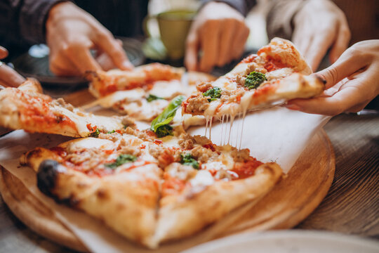 Three firends together eating pizza in a cafe