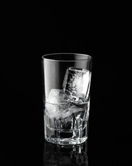Glass with ice and water on black background