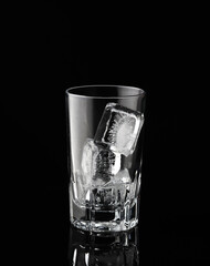 Ice cubes in empty glass on black background. Glass of water or whiskey and wine. Empty glass for alcoholic beverages