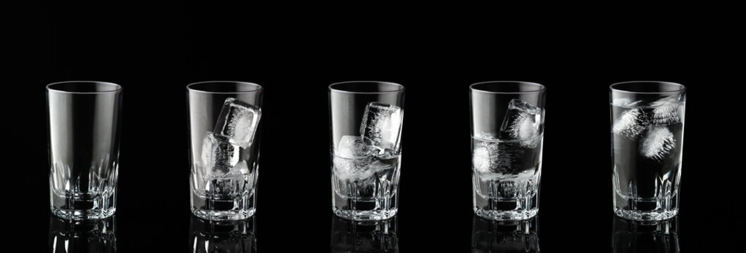 Collection of water with ice cubes in glass on black background.