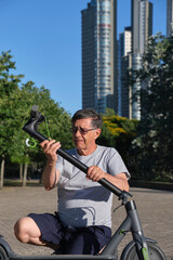 Hispanic senior man unfolding his electric scooter outdoors, active living