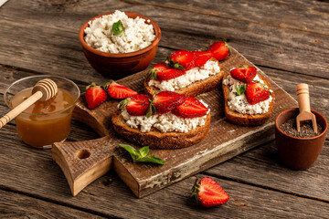 toasts or bruschetta with strawberry and mint on cream cheese ricotta. Delicious breakfast or snack, top view