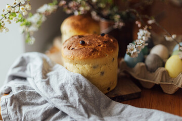 Homemade easter bread, natural dyed eggs and spring blossom on rustic table in room. Happy Easter! Freshly baked easter cake, traditional ukrainian bun
