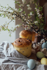 Happy Easter! Homemade easter bread, natural dyed eggs and spring blossom on rustic table in room. Freshly baked easter cake, traditional ukrainian bun