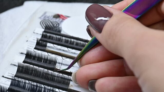 Beauty salon. The work of a master of eyelash extension. The master selects the eyelashes, straightens them for proper gluing.