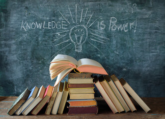 open book, blackboard with drawing of a lightbulb and slogan knowledge is...