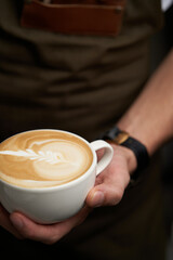 Barista hands pouring milk in coffee cup, close-up