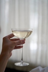 Woman hand holding glass with martini cocktail, close-up