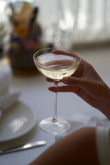 Woman hand holding glass with martini cocktail, close-up