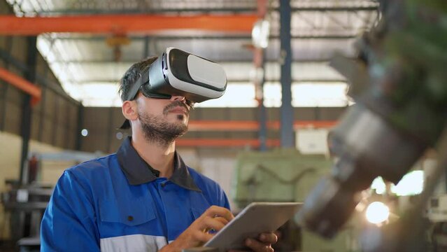 Engineer wearing virtual reality headset standing in the manufacturing factory. Moving hand and looking around the data. Working with Holographic Animations. High technology and industrial concept