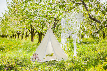 Photo zone for a children's photo shoot in a spring blooming garden - wigwam, crocheted dream...