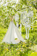Photo zone for a children's photo shoot in a spring blooming garden - wigwam and crocheted dream catchers © Kathleen