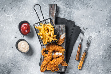 Breaded chicken strips with french fries and ketchup. Gray backgrund. Top view