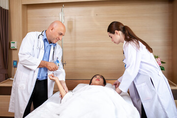 Group of doctor visiting ward have woman patient and check her with stethoscope on bed. Woman patient lying on hospital bed while doctor giving her checkup.