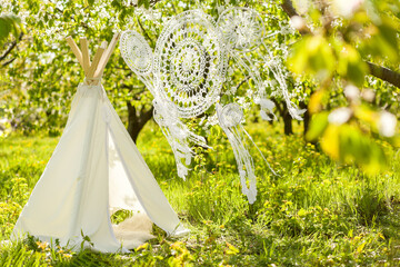 Photo zone for a children's photo shoot in a spring blooming garden - wigwam and crocheted dream catchers