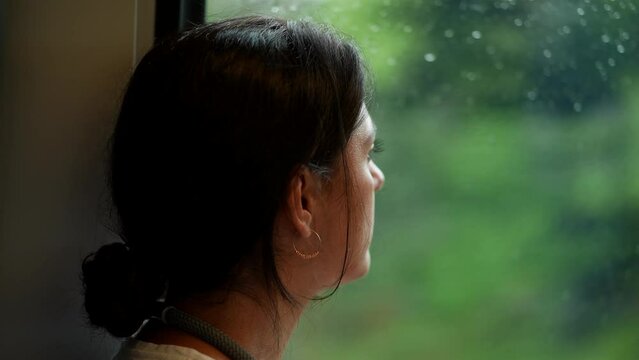 Woman riding train commuting to work or study Girl looking out train window starring at landscape view passing by