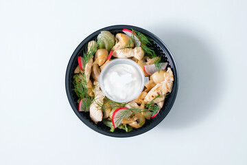 Vegetable salad with tomatoes mushrooms and sauce in a disposable bowl.