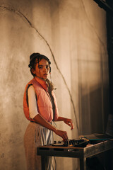 Portrait of an attractive female DJ at work, playing a music set at a party. The lady in the...