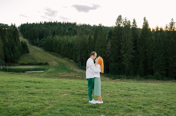 Portrait of a happy young woman holding her boyfriend's hand while walking in the mountains on vacation. Couple enjoying a hike in nature.