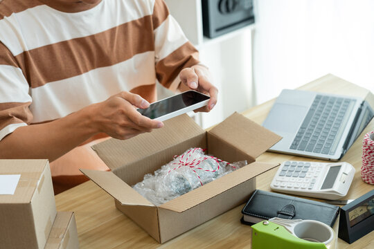 Online shopping concept the merchant using his mobile phone to take a picture of his product in the box
