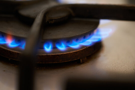 Gas stove being turned on by a lit burner. Natural gas concept.