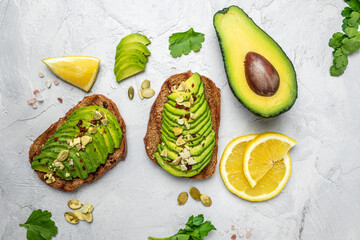 Healthy avocado toasts for breakfast or lunch with rye bread, sliced avocado, pumpkin seeds, salt and pepper. Vegetarian food. Plant-based diet. Clean eating. Top view. Copy space