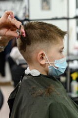 Children's haircut in the barbershop, stylish and modern haircut for schoolchildren, work during...