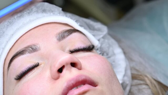 The master performs the procedure of eyelash extensions. Completion of the work. All the eyelashes are glued. The master removes the gasket