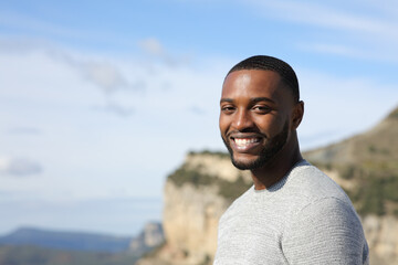 Happy man with black skin looking at camera in nature
