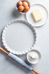 Empty tart form and tart ingredients on white backgound. White table with empty tart form