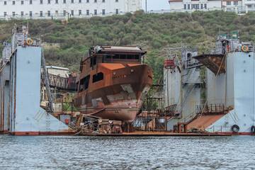 Rusty vessel is being repaired in the port at a ship repair facility. Shipyard.