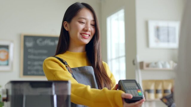 Customer using credit card for payment to owner at cafe restaurant, cashless technology and credit card payment concept