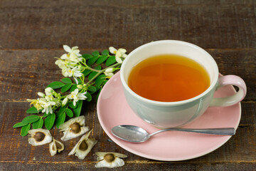 Moringa Tea in ceramic cup with fresh green leaf and flower on wooden background. Moringa oleifera tropical herb healthy lifestyle concept.