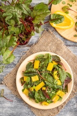 Vegetarian salad of yellow pepper, beet microgreen sprouts on gray. Top view, close up.